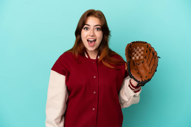 Young redhead woman playing baseball isolated on blue background with surprise facial expression - Foto, Bild