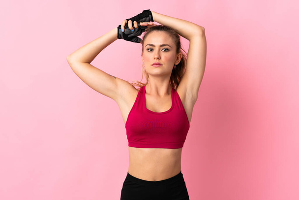 Young Brazilian woman isolated on pink background stretching - Photo, Image