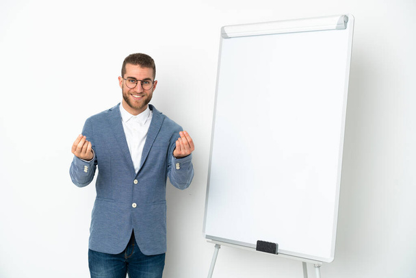 Young business woman giving a presentation on white board isolated on white background making money gesture - Photo, image