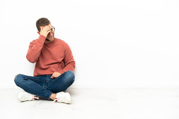 Mladý pohledný muž sedí na podlaze a směje se - Fotografie, Obrázek