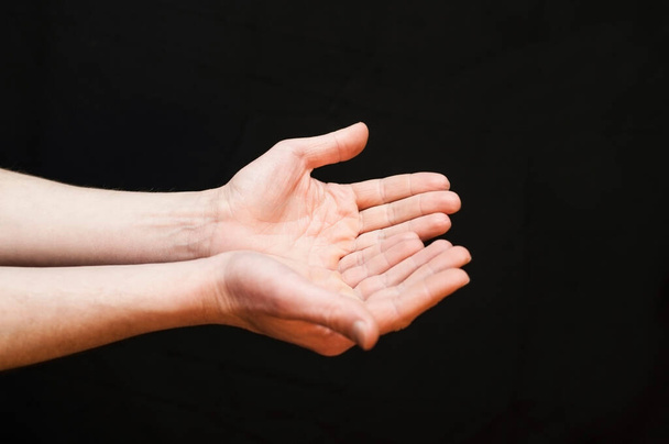 Extending hands forward asking something or giving a black background - Fotó, kép