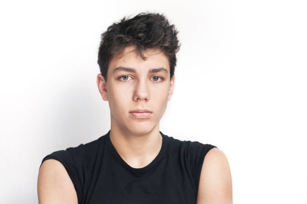 Portrait of a beautiful teenager in a black t-shirt with a serious face on a white background. Isolated. Copy space - Foto, Imagen