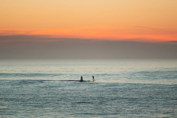 Jet ski towing a foil surfer during the sunset on atlantic ocean - Фото, изображение