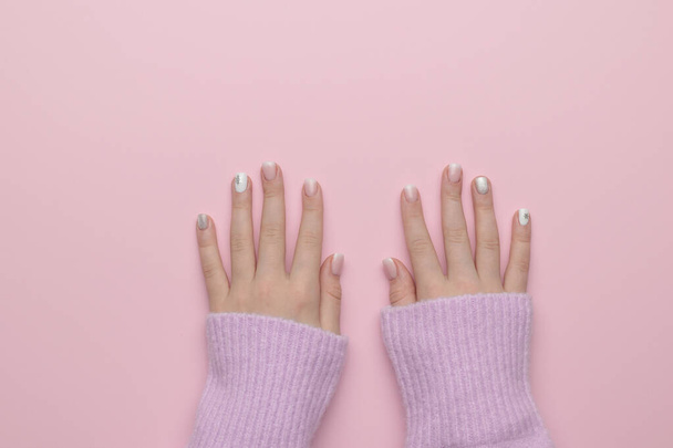 The hands of a girl in a warm sweater on a pink background. Manicure. The beauty of women's hands. Flat lay. - Fotó, kép