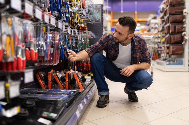 male buyer in a hardware store chooses pliers and nippers for construction work - Foto, Bild