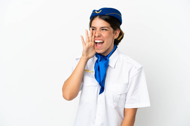 Airplane stewardess caucasian woman isolated on white background shouting with mouth wide open to the lateral - Foto, immagini