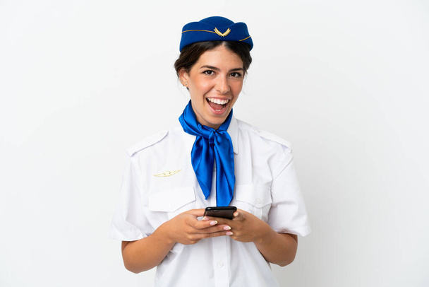 Flugzeug Stewardess kaukasische Frau isoliert auf weißem Hintergrund überrascht und sendet eine Nachricht - Foto, Bild