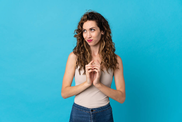 Young caucasian woman isolated on blue background scheming something - Photo, Image