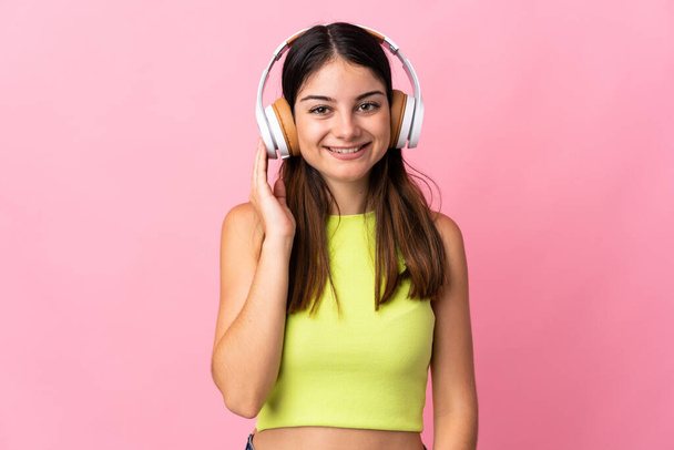 Молода біла жінка ізольована на рожевому фоні прослуховування музики
 - Фото, зображення