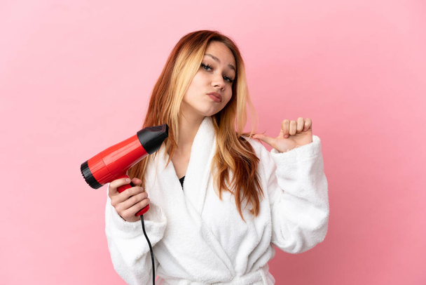 Teenager blonde girl holding a hairdryer over isolated pink background proud and self-satisfied - Foto, immagini