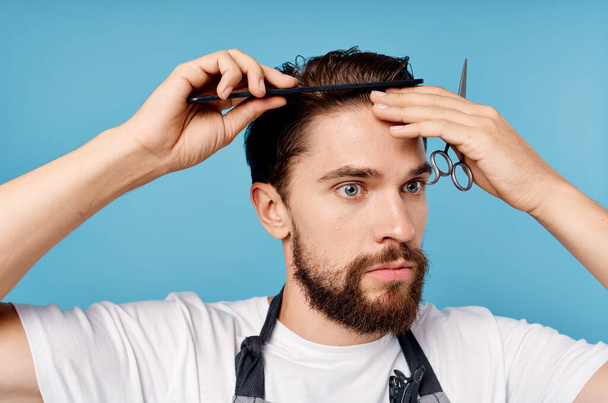professional hairdresser with comb in hand scissors haircut model blue background - Zdjęcie, obraz