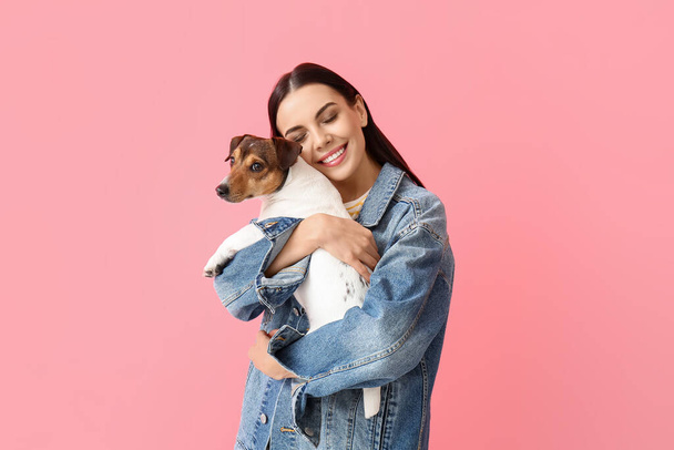Щаслива молода жінка з милою собакою на рожевому фоні
 - Фото, зображення