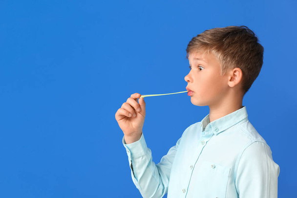 Cute little boy chewing gum on blue background - Φωτογραφία, εικόνα