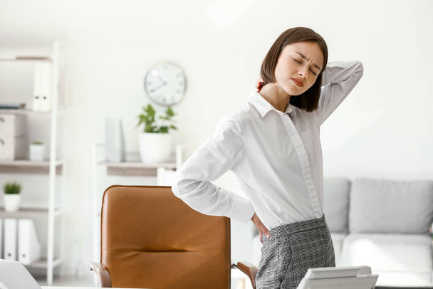 Young woman feeling back pain in office - Valokuva, kuva