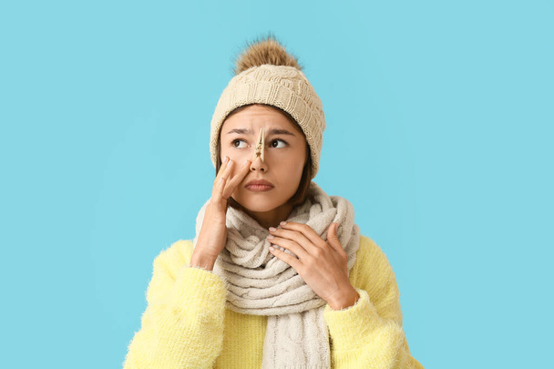 Ill young woman with clothespin on her nose against color background - Foto, Imagem