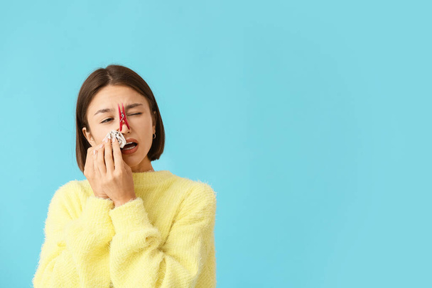 Nemocná mladá žena s špendlíkem na nose na barevném pozadí - Fotografie, Obrázek