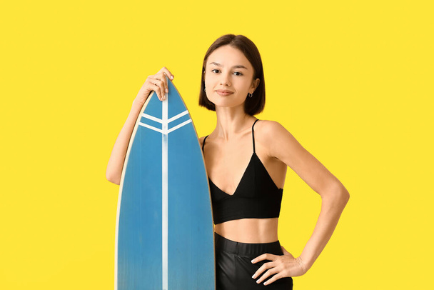 Beautiful young woman with surfboard on color background - 写真・画像