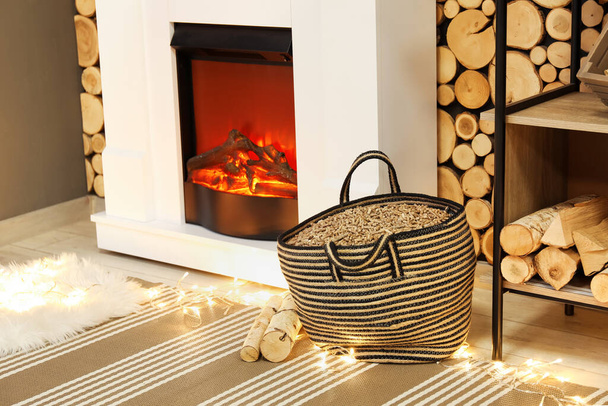 Bag with pellets and woods near fireplace in living room - 写真・画像