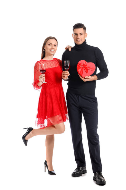 Ευτυχισμένο νεαρό ζευγάρι με δώρο και κρασί σε λευκό φόντο. Γιορτή του Αγίου Βαλεντίνου - Φωτογραφία, εικόνα