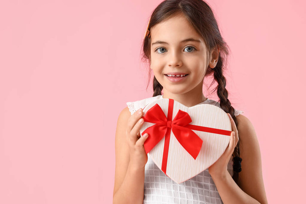 Funny little girl with gift on color background. Valentine's Day celebration - 写真・画像