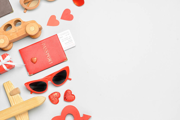 Hermosa composición para el Día de San Valentín con juguetes de madera, pasaporte, gafas de sol y corazones sobre fondo claro - Foto, Imagen
