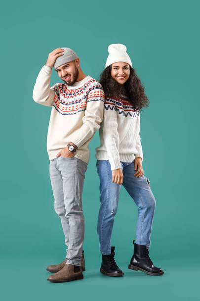 Happy young couple in warm sweaters on color background - Фото, изображение