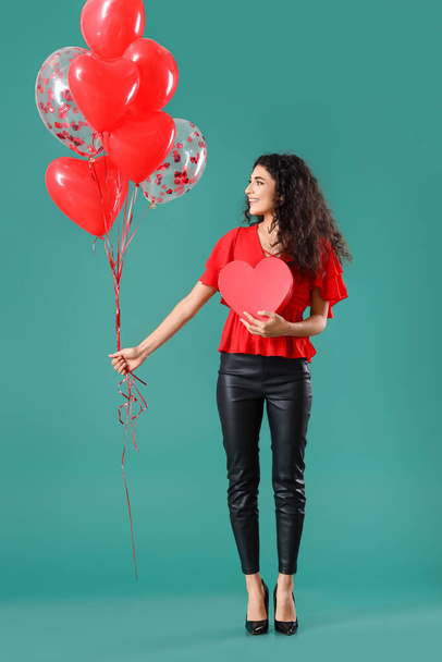 Beautiful young woman with gift and balloons on color background. Valentine's Day celebration - Foto, imagen