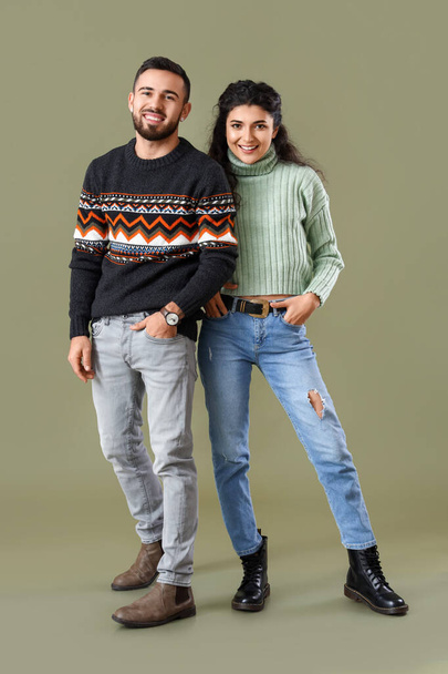 Feliz pareja joven en suéteres cálidos sobre fondo de color - Foto, imagen