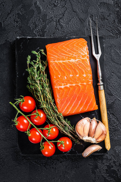 Protein vegetarian diet - raw salmon fillet steak with herbs and tomato. Black background. Top view - Фото, зображення