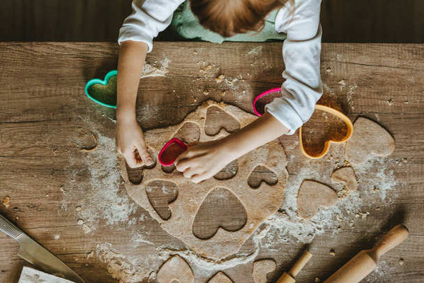 Mała dziewczynka cięcia serca kształt ciasteczka z ciasta żytniego - Zdjęcie, obraz