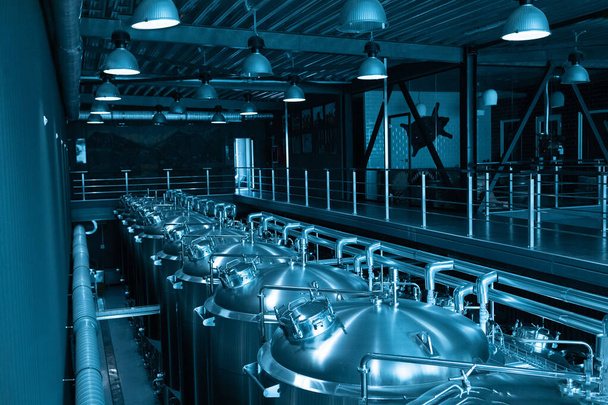 Przemysłowe wnętrze nowoczesnego browaru rzemieślniczego z chromowanymi cylindrycznymi metalowymi zbiornikami piwa. Prywatny minibrowar. - Zdjęcie, obraz