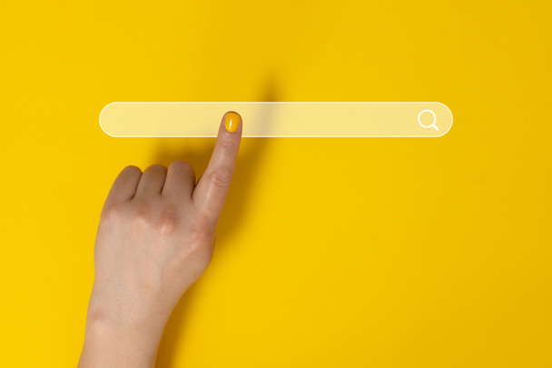 Vrouw wijst naar iets op gele achtergrond, close-up. Vingers aanraken zoekknop met vergrootglas - Foto, afbeelding