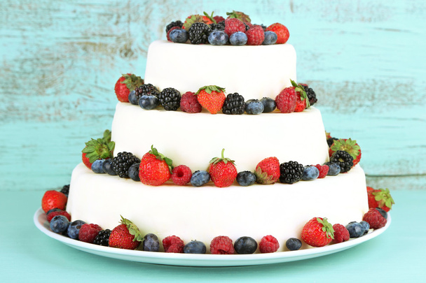 Beautiful wedding cake with berries on color wooden background - Foto, Imagen