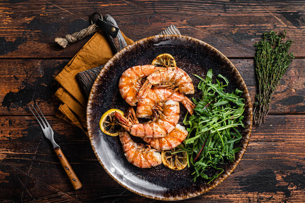 Spicy garlic Giant shrimps prawns in plate with salad. Wooden background. Top view - Φωτογραφία, εικόνα