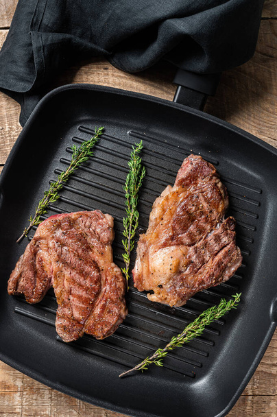 Grilled Chuck eye Roll beef steaks with herbs on grill skillet. Wooden background. Top view - Valokuva, kuva