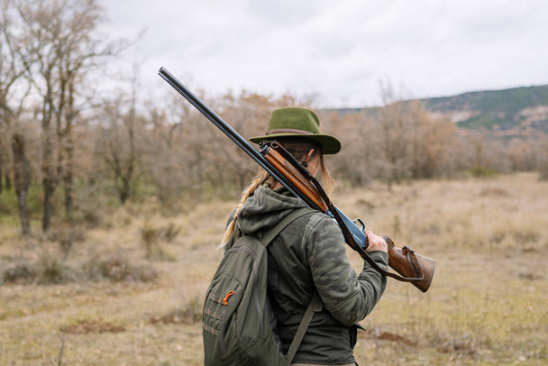 Mujer cazadora con escopeta cazando en el campo. - Foto, Imagen