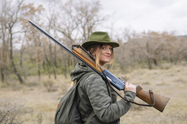 Hunter vrouw met jachtgeweer in het veld. - Foto, afbeelding