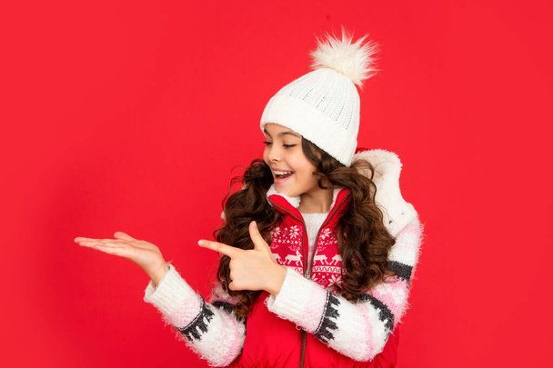presenting copy space. amazed kid with curly hair in christmas waistcoat and hat. teen girl - Foto, Bild