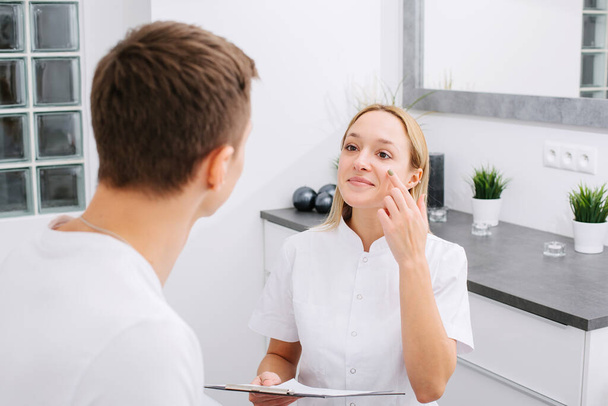 Consultation in cosmetology clinic. Female professional beauty doctor talking with pretty young men. - Foto, Imagem