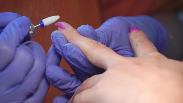 Manicure master in blue gloves removes gel polish from nails using a cutter. - Filmagem, Vídeo