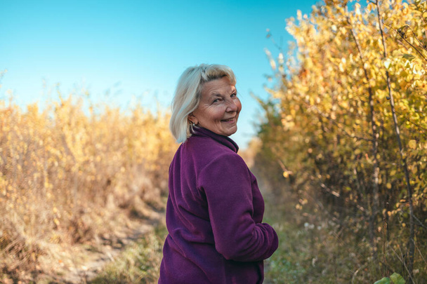 Portret szczęśliwej, aktywnej, pięknej starszej kobiety biegającej rano na świeżym powietrzu w jesiennym lesie - Zdjęcie, obraz
