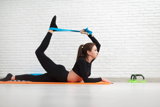 het meisje voert een home workout stretching om haar rug te versterken - Foto, afbeelding