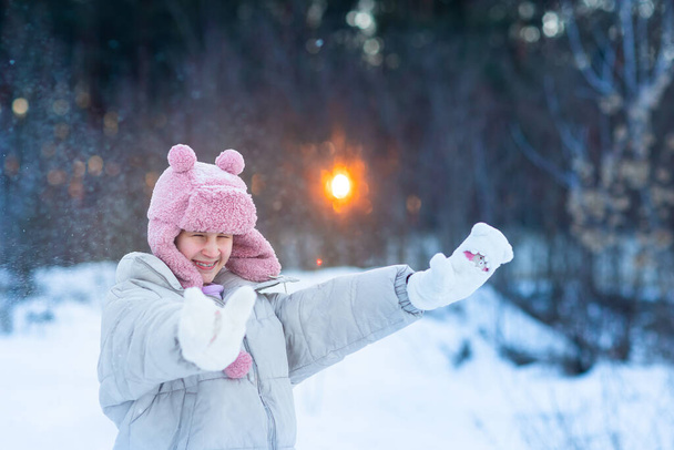 Cute little teenage girl having fun playing with snowballs, ready to throw the snowball. Snow games. Winter vacation. - Foto, imagen