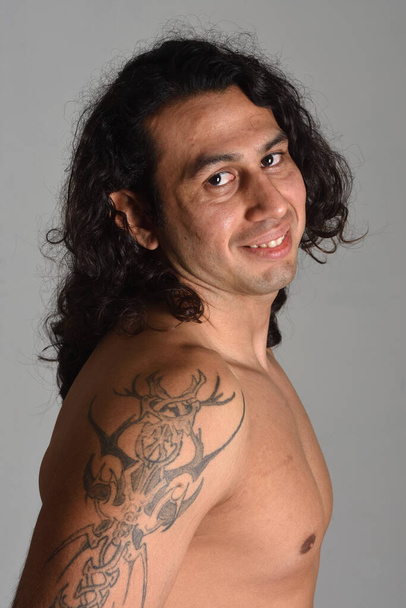 κοντινό πλάνο ενός πορτραίτου ενός άνδρα με τατουάζ που κοιτάζει την κάμερα σε γκρι φόντο - Φωτογραφία, εικόνα