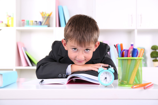 Schoolboy sitting at table in classroom - Foto, immagini