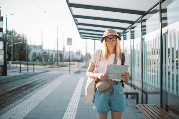 若い観光客の女性は、ヨーロッパを旅し、街の通りにバス停で屋外で手の地図を渡します。観光地のコンセプト - 写真・画像
