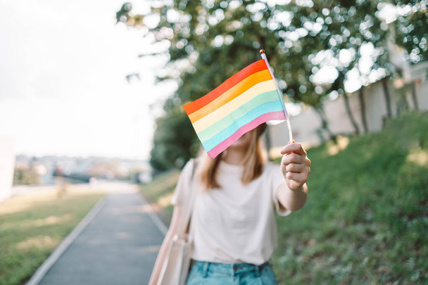 Beautiful caucasian lesbian woman holding rainbow flag during pride parade at street - Фото, изображение