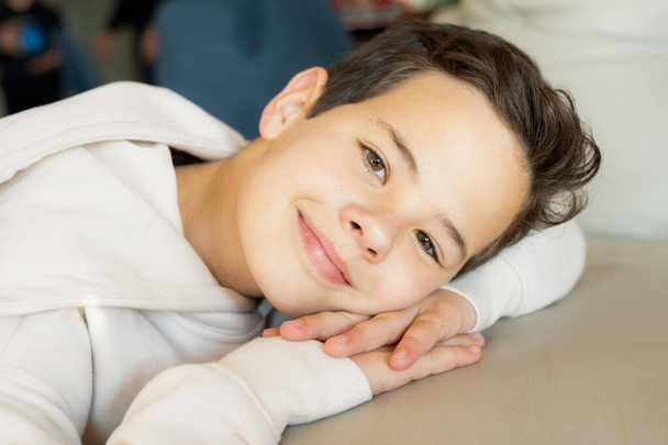 Close up portrait cute smiling boy lying on sofa at home - Foto, afbeelding