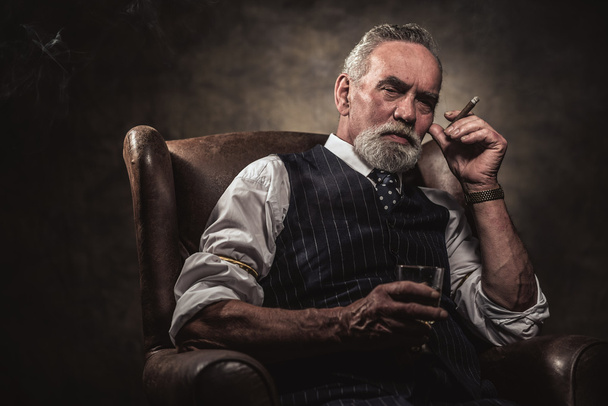 Dans la chaise assis homme d'affaires senior avec cigare et whisky. Gris
 - Photo, image
