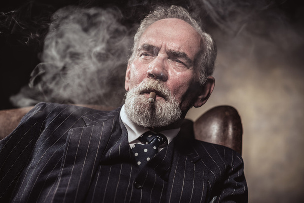 特徴的なシニア ビジネスの男が座って椅子で喫煙たばこ - 写真・画像
